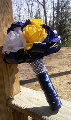 a bridal bouquet with yellow and white flowers on a wooden bench in the woods