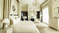 an elegant bedroom with white furniture and chandelier