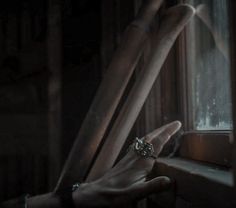 a person's hand holding onto the handle of a window in a dark room