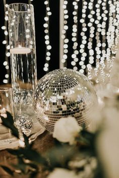 a disco ball sitting on top of a table next to a tall vase filled with flowers