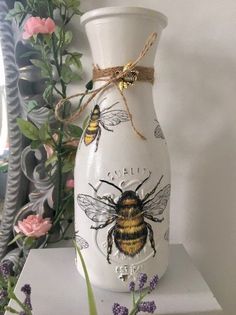 a white vase sitting on top of a table filled with flowers and bees painted on it