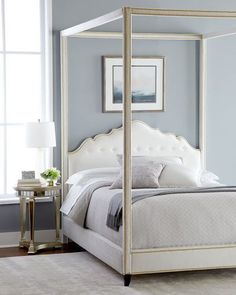 a white four poster bed in a bedroom with blue walls and carpeted flooring