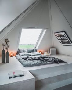 an attic bedroom with slanted ceilings and white walls, has a large bed in the corner