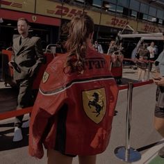 a woman in a red jacket standing next to a fence