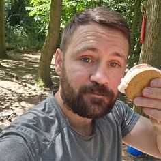 a man eating a hot dog in the woods