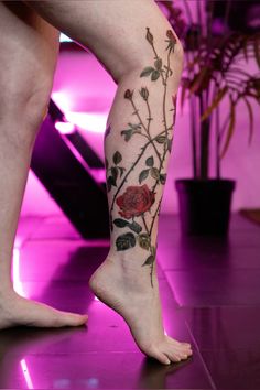 a woman's legs with tattoos and flowers on the bottom part of her leg