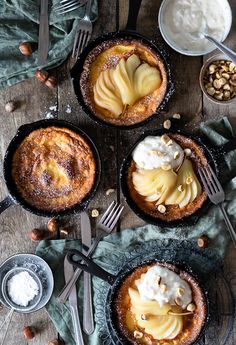 three pies with apples and whipped cream in them on top of a wooden table