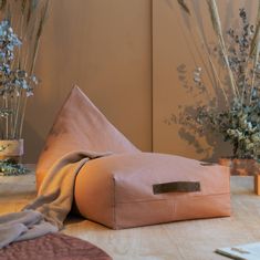 a large pillow sitting on top of a wooden table next to vases with flowers