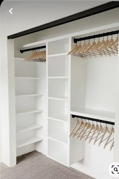 an empty closet with white shelves and wooden hangers