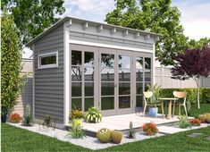 a small garden shed with glass doors on the front and side windows, surrounded by landscaping