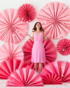 a woman standing in front of pink paper fans