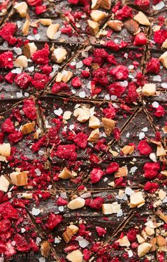 chocolate and raspberry tart with white sugar on top, topped with chopped nuts