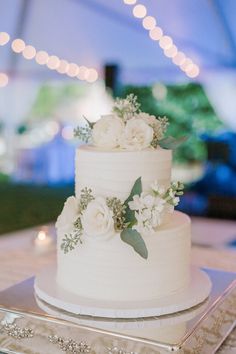 a white wedding cake with purple flowers and greenery