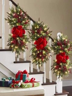 christmas decorations on the banisters and stairs with presents under them in red bows