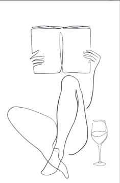 a person sitting on the floor reading a book with a glass of wine next to it