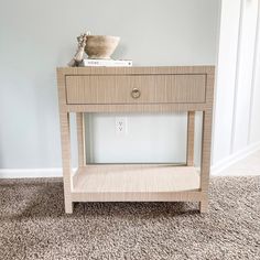 a wooden table sitting on top of a carpeted floor next to a white wall