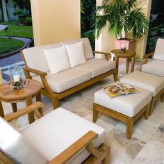 a living room filled with lots of furniture next to a large glass window covered in greenery