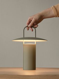 a person holding a light on top of a wooden table