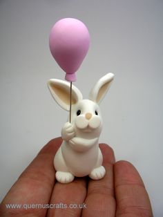 a small toy rabbit holding a pink balloon in its hand with it's tail