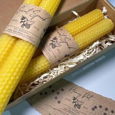 three yellow corn cobs in a cardboard box with labels on them and some other items