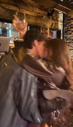 a man and woman kissing in front of a laptop computer on a table next to a fireplace