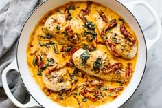 chicken with spinach and cheese in a white skillet on a marble countertop