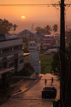 two people are riding their bikes down the street as the sun sets in the background