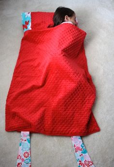 a baby wrapped in a red blanket laying on the floor