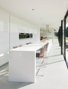 a kitchen with white countertops and chairs next to an outdoor dining area that has sliding glass doors on both sides