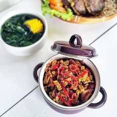 a bowl filled with food sitting next to another bowl full of vegetables and meats