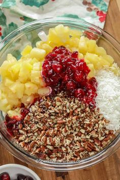 ingredients for cranberry sauce in a glass bowl on a wooden table with cherries and pecans