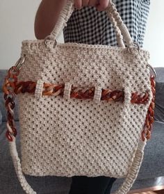 a woman is holding a crocheted purse