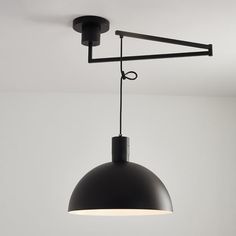 a black light fixture hanging from the ceiling in a room with white walls and flooring