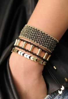 a person wearing three different bracelets on their arm and one has a black leather jacket