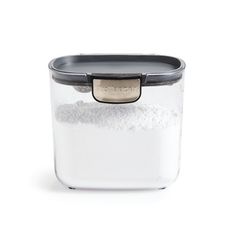 a glass container filled with white powder on top of a white table next to a black lid