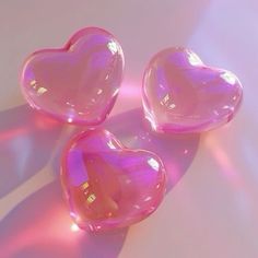 three pink heart shaped soaps sitting on top of a white surface with the light shining through them