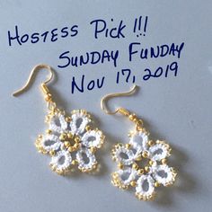 a pair of white and gold earrings sitting on top of a table next to a sign that says hostess pick