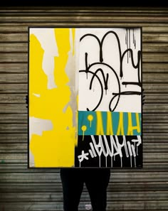 a man holding up a large piece of art with graffiti on it's sides