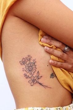 a woman's back with a flower tattoo on her left side ribcage