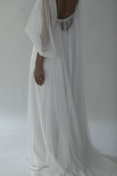 the back of a woman's white dress with sheer sleeves and an open neckline