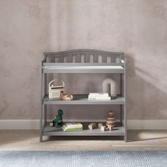 a grey shelf with toys and books on it in front of a wall painted beige