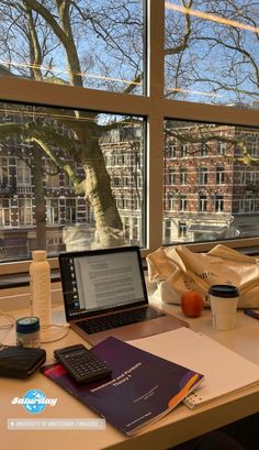 an open laptop computer sitting on top of a desk next to a cup of coffee