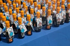 several bottles of wine are lined up on a blue table cloth with tags attached to them