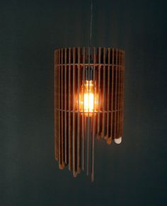 a wooden lamp hanging from the ceiling in a dark room with black walls and flooring