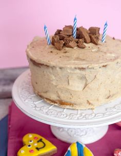 there is a cake with candles on it and cookies around the cake plate next to it