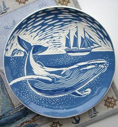 a blue and white plate with an image of a whale in the ocean on it