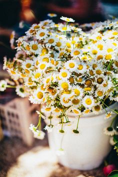 a white vase filled with lots of yellow and white flowers