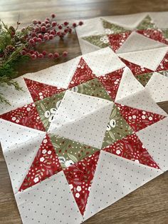 two christmas quilts sitting on top of a wooden table