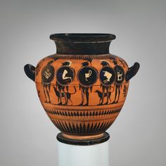 an old vase with people on it sitting on a pedestal in front of a gray background