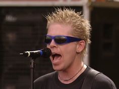 a man with sunglasses on singing into a microphone